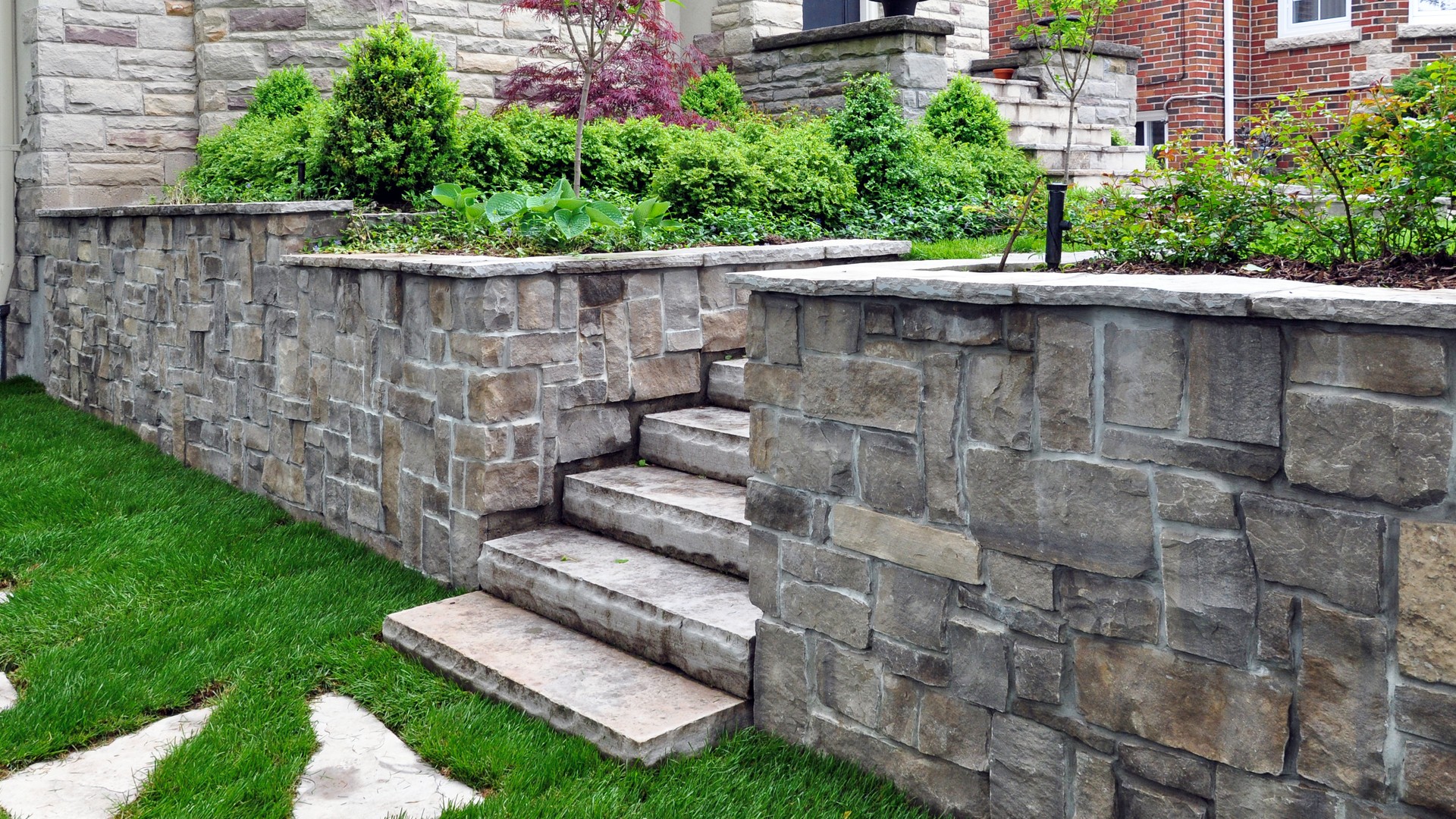 Luxury landscaping features a retaining wall and natural stone steps.